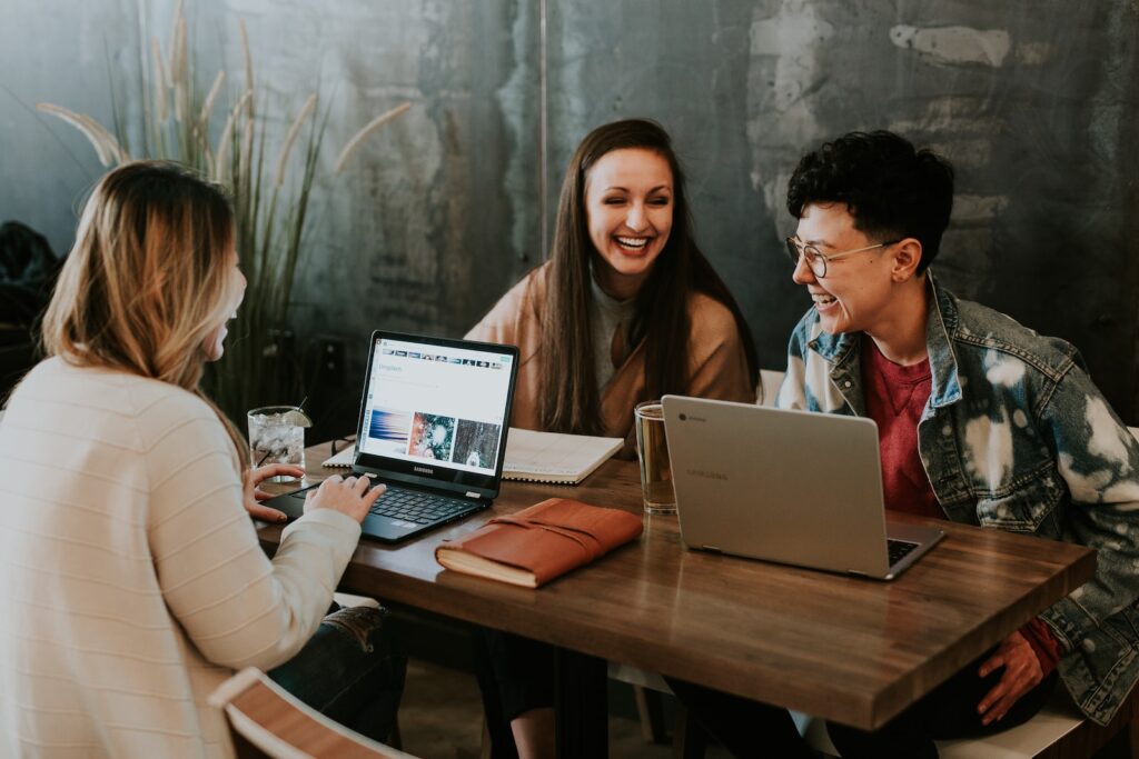 Three people sitting in front of table laughing together