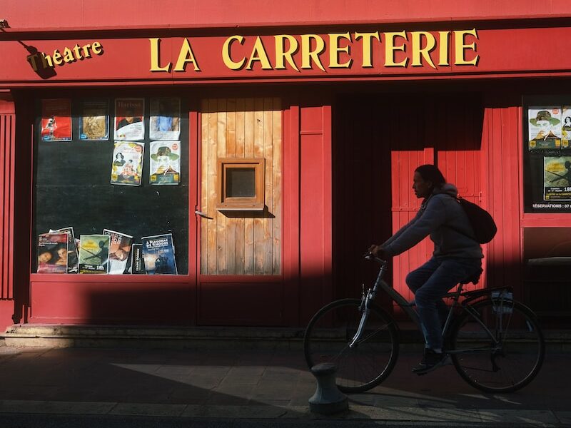 a man riding a bike past a red building